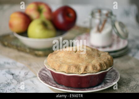 Hausgemachtes Apfelkuchen mit frischen Äpfeln und Zimt-Zucker im Hintergrund. Stockfoto