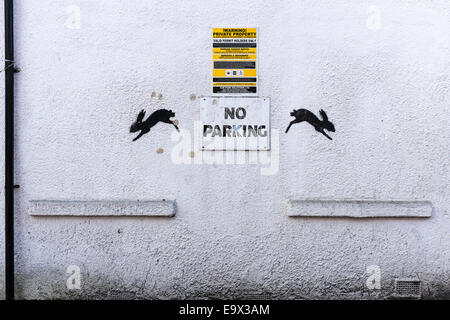 Eine weiße Wand mit einem Warnhinweis für "Parkverbot" und zwei Lotnummer schwarze Kaninchen. Stockfoto