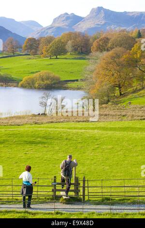 Touristen über einen Stil neben einem Fußweg auf Loughrigg Tarn, The Lake District, Cumbria, England, UK. Stockfoto