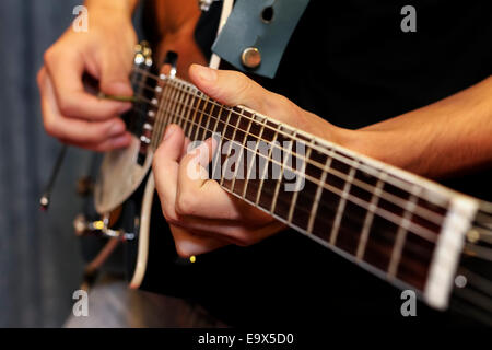 Schuss von einem Mann mit seinen Fingern auf den Bünden einer Gitarre spielen hautnah Stockfoto