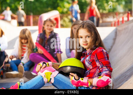 Mädchen hält Helm tragen Inline - Skates sitzen Stockfoto