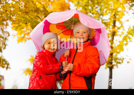 Jungen und Mädchen zusammenhalten Regenschirm unter Regen Stockfoto