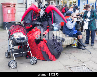 Eine Frau in einem aufblasbaren Fledermaus Kostüm sitzt mit einer Babypuppe gekleidet als Goten auf der Whitby Gothic Woche Ende Herbst 2014 Stockfoto