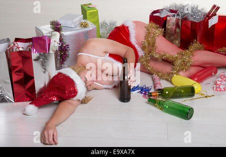 Weibliche Partei-Goer auf dem Boden trägt ein Kostüm Santa Outfit und Alkohol zu trinken Stockfoto