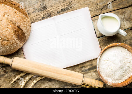 Geöffnete Kochbuch mit Bäckerei Hintergrund auf Holztisch. Rezept- und Menü-Hintergrund Stockfoto
