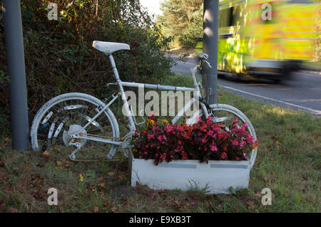 Gefahr. Ein weiß lackiert Ghost Bike und Blumen, die Kennzeichnung der Stelle, wo ein Radfahrer getötet oder bei einem Verkehrsunfall verletzt wurde. Dorset, England Stockfoto