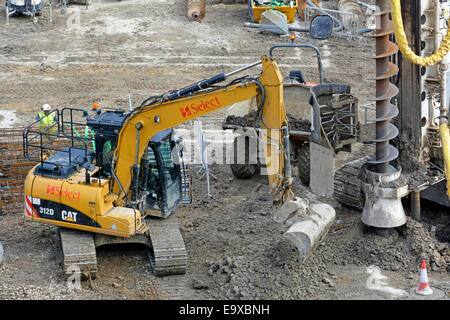 Nahaufnahme der Raupenlegermaschine von Caterpillar reinigt die Erde vom Bohrkopf der Aufwickelanlage Kegelmarkierungen des fertigen Pfahls London England Großbritannien Stockfoto