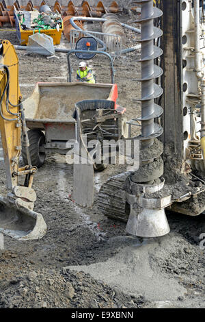 Digger & Dumper Truck & Pumped Beton Spews aus voller Schnecke Haufen Bohrung Fundament Wohnbau Baustelle London England UK Stockfoto