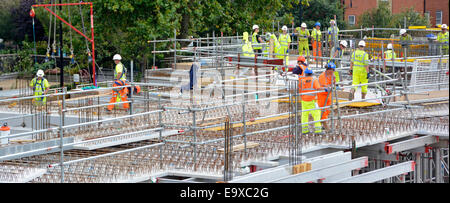 Arbeiter beschäftigt Baustelle arbeiten zusammen auf Betonfertigteil Bodenplatte hoch vis Jacke Harthut Sicherheit & rot Tethering Ausrüstung Großbritannien Stockfoto