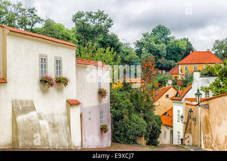 Gebäude und Häuser im historischen Zentrum von Prag. Grüne Bäume, Lampen, Blumen im Topf auf den Fenstern, roten Dächern Stockfoto