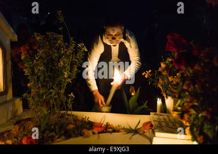 Oaxaca, Mexiko. 1. November 2014. Ein Mann verlässt Kerzen und Blumen auf das Grab eines Angehörigen auf dem Friedhof Xoxocotlan am Dia de Los Muertos. Nick St.Oegger/ZUMA © Wire/ZUMAPRESS.com/Alamy Live-Nachrichten Stockfoto