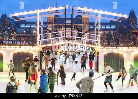 Eislaufen auf der Eisbahn vor dem Rijksmuseum Rijks Museum Amsterdam. Logo ich Amsterdam sichtbar hinter einer Modell-Zugbrücke. Stockfoto