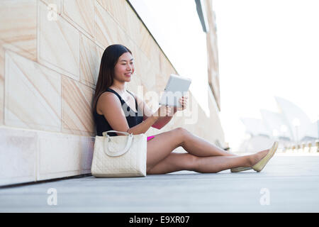 Eine junge Frau, entspannend, während auf einem Tablettgerät Inhalte betrachten Stockfoto