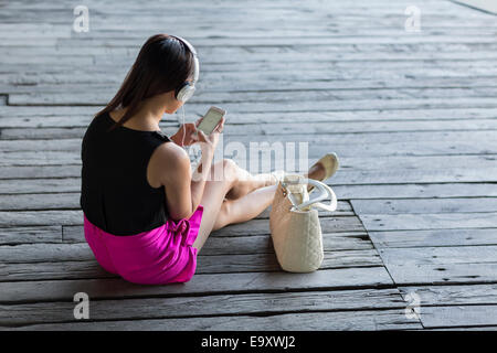Eine junge Asiatin konsumieren von Inhalten auf ihr Smartphone im freien Stockfoto