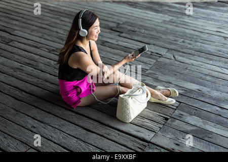 Eine junge Asiatin konsumieren von Inhalten auf ihr Smartphone im freien Stockfoto