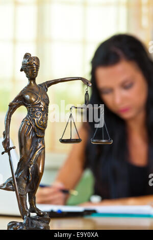 Ein erfolgreicher Anwalt im Büro von Gerechtigkeit Figur im Vordergrund. Stockfoto