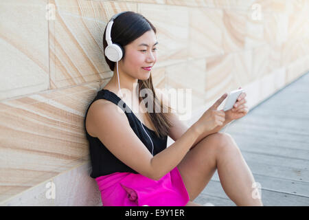 Eine junge asiatische Frau, die mit ihrem mobilen Gerät Stockfoto