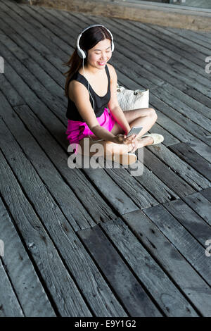 Eine junge asiatische Frau, die mit ihrem mobilen Gerät Stockfoto