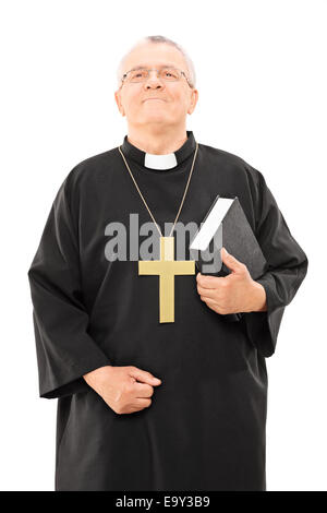 Reife Priester isoliert halten eine Bibel und blickte auf weißem Hintergrund Stockfoto