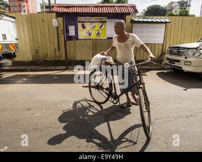 Yangon, Yangon Division, Myanmar. 4. November 2014. Ein burmesische Mann schiebt sein Fahrrad vorbei ein Plakat in Yangon Warnung Menschen über das Ebola-Virus. Es wurden keine gemeldeten Fälle von Ebola-Virus in Myanmar und gibt es keine Direktflüge zwischen Ebola endemische Teilen von Afrika und Myanmar, aber die Regierung von Myanmar die Plakate in Yangon als Vorsichtsmaßnahme. © Jack Kurtz/ZUMA Draht/Alamy Live-Nachrichten Stockfoto