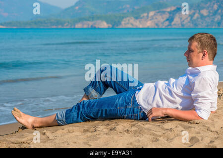 männliche Geschäftsmann am Strand in der Nähe des Meeres liegen Stockfoto