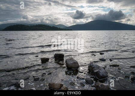 Ein Landschaftsbild der Ufer von Loch Lomond in den schottischen Highlands Scotland UK zeigt Felsen im Vordergrund. Stockfoto