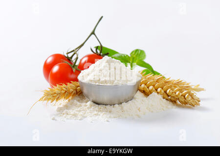 Schüssel mit fein gemahlenem Mehl, Ähren und frische Tomaten - Stillleben Stockfoto