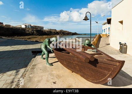 Boot mit Statuen von Fischern am alten Hafen in diesem NW Küste Dorf; El Cotillo, Fuerteventura, Kanarische Inseln, Spanien Stockfoto