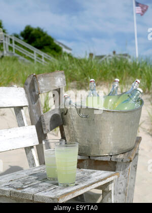 Gläser und Flaschen von Zitrone Aide am Strand Stockfoto