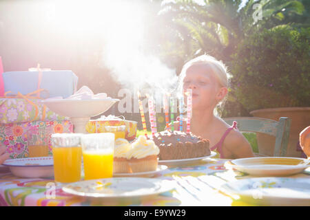 Mädchen bläst Kerzen auf Geburtstagskuchen Stockfoto