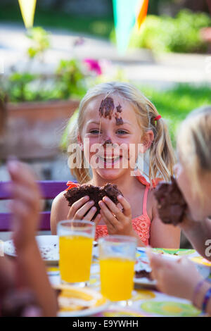 Mädchen essen Schokolade Kuchen, Gesicht mit Zuckerguss bedeckt Stockfoto