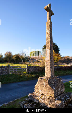 Der letzte Abend Sonnenlicht fällt auf das 14. Jahrhundert Wegkreuz in Cotswold Dorf von Condicote, Gloucestershire Stockfoto