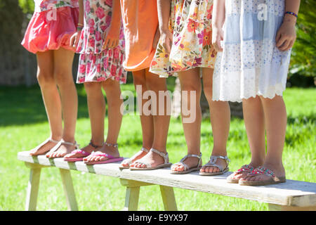 Zugeschnittenen Schuss der Beine von fünf Mädchen stehen auf Gartenbank Stockfoto