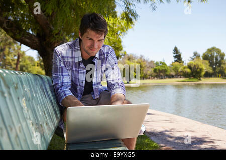 Mann mit Laptop auf Parkbank Stockfoto