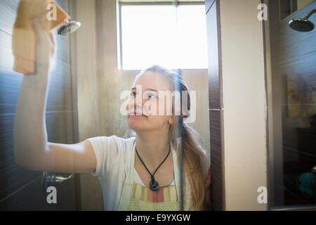 Junge Frau, die Reinigung des Badezimmers mit grünen Reinigungsmittel Stockfoto