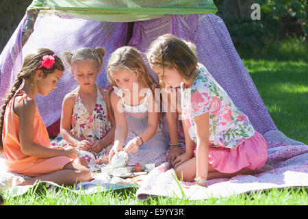 Fünf Mädchen spielen mit Spielzeug-Tee-Set im Garten Stockfoto