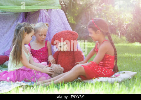 Drei Mädchen spielen mit Teddybären im Garten Stockfoto