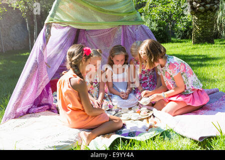 Fünf Mädchen spielen mit Spielzeug-Tee-Set vor Tipi Stockfoto