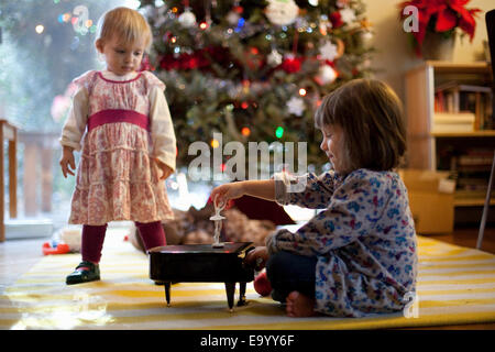 Zwei junge Schwestern anhören Spielzeugkiste Klavier Musik zu Weihnachten Stockfoto