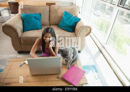 Frau auf Smartphone mit Laptop zu Hause Stockfoto