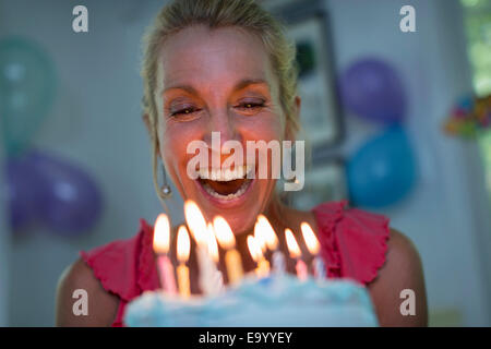 Reife Frau hält Geburtstagstorte mit Kerzen Stockfoto