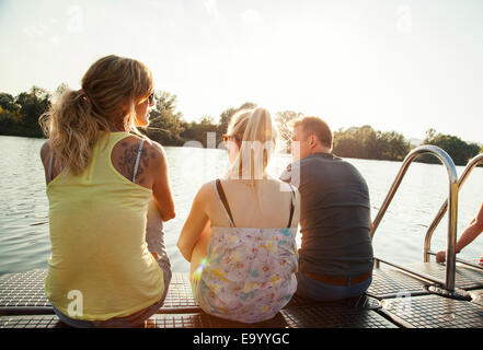 Drei junge Erwachsene Freunde blicken Sie von riverside pier Stockfoto