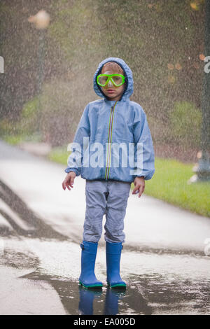 Porträt eines jungen tragen Scuba Schutzbrillen und Kautschuk Stiefel stehen in Straße Pfütze Stockfoto