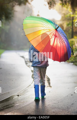 Rückansicht des jungen mit Regenschirm auf Straße Stockfoto