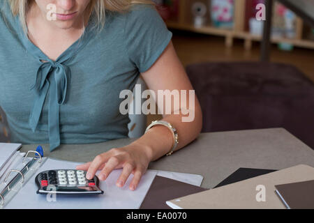 Zugeschnittenes Bild der Verkäuferin mit Taschenrechner im Schreibwarengeschäft Stockfoto