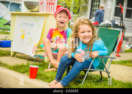 Candid Porträt von zwei lächelnde Mädchen verkaufen Limonade und Popcorn am Yard sale Stockfoto