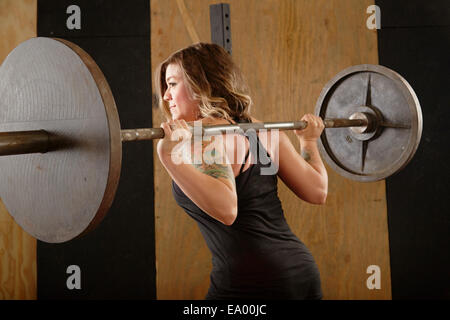 Junge Frau, die Hantel heben, im Fitness-Studio Stockfoto