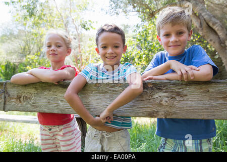 Drei Kinder in beugte sich über den Gartenzaun Stockfoto