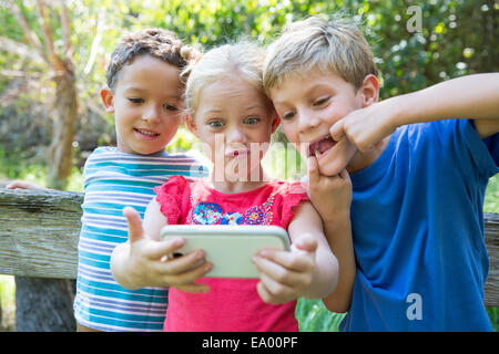 Drei Kinder im Garten nehmen Selfie auf smartphone Stockfoto