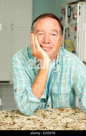 Reifer Mann sitzt in der Küche Stockfoto